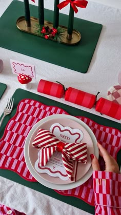 a table set for christmas with red and white plates, napkins and place settings