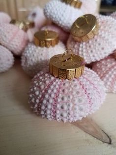 some pink and white knitted balls with gold trimmings on the top one