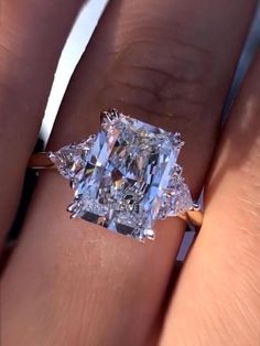 a woman's hand holding an engagement ring with a large diamond in the center