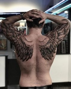 a man with wings on his back is looking at the camera while holding his hands to his head