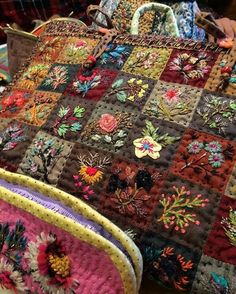 two purses sitting next to each other on top of a wooden table covered in fabric