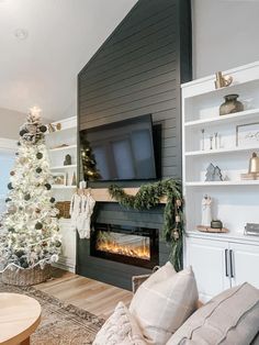 a living room with a christmas tree, fireplace and tv on the wall in front of it