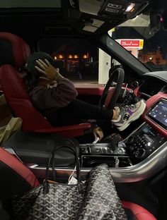 a woman sitting in the driver's seat of a car holding her hand up to her face