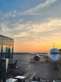 an airplane sitting on the tarmac at sunset