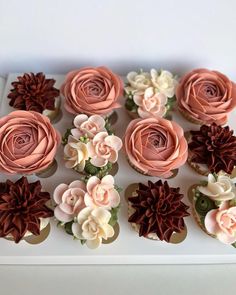 cupcakes decorated with pink and brown flowers on a white tray, ready to be eaten