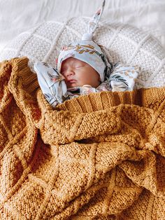 a baby wrapped in a blanket on top of a bed