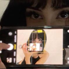 a woman holding up a cell phone to take a photo with her face on the screen