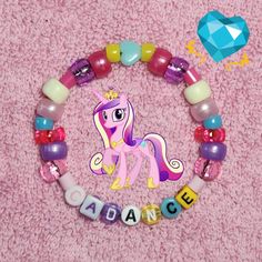 a pony beaded bracelet with the word dance spelled out in small letters on a pink background