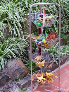 three tiered metal plant stand with plants in the background