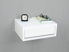 a white nightstand with a clock and glasses on it next to a pair of eyeglasses