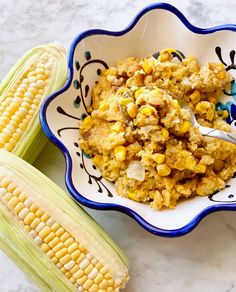 corn on the cob in a bowl with a spoon next to it and another dish