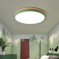 a bedroom with green walls and mountains painted on the wall, along with a round ceiling light