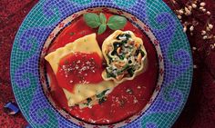 a blue plate topped with ravioli and sauce on top of a red table cloth