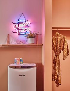 a pink room with a neon sign above the refrigerator