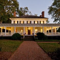 a large white house sitting on top of a lush green field