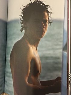 an open book with a man without a shirt on it's cover and water in the background