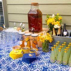 a table topped with lots of bottles and glasses filled with liquid on top of a blue cloth