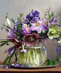 a glass vase filled with purple and green flowers