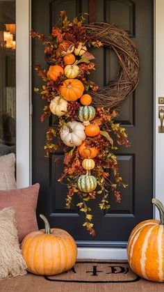 a front door decorated for fall with pumpkins and gourds