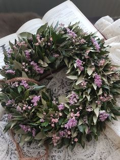 a wreath is laying on top of an open book with pink flowers and greenery