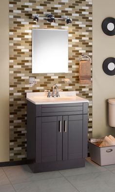 a bathroom vanity with a mirror above it and a towel dispenser on the wall