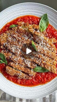 a white bowl filled with tomato sauce and garnished with parmesan cheese