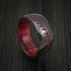 a baseball ring with red stitching on it sitting on top of a wooden table