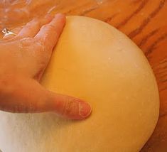 a person's hand on top of a ball of dough