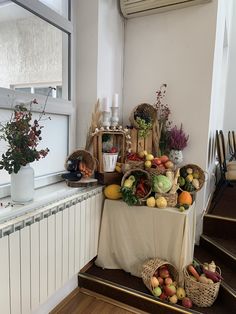 there is a table full of fruits and vegetables on the floor in front of a window