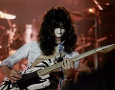 a man with long hair playing an electric guitar