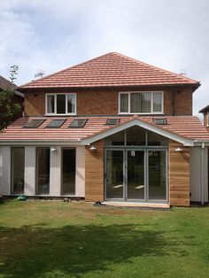 a house that has some windows on the side of it and grass in front of it