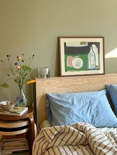 a bed with blue and white sheets in a bedroom next to a table with flowers