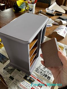 a person holding a piece of cardboard in front of a microwave oven on top of a table