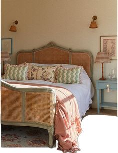 a bedroom with wicker headboard and pink bedding, two lamps on either side of the bed