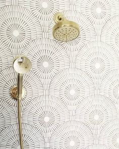 a shower head and thermostaer on a wall in a bathroom with circular designs