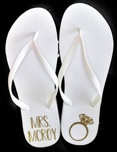 two pairs of white flip flops with gold lettering on them