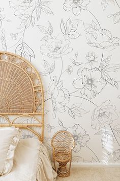 a wicker chair sitting next to a wall with flowers on it