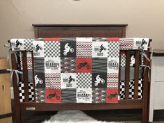 a baby crib with a motor bike quilt on it's cover and sheepskin rug