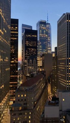 the city skyline is lit up at night, with skyscrapers in the foreground