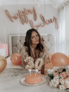 a woman sitting at a table in front of a cake with the number twenty on it