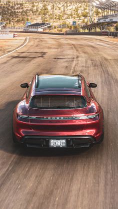 a red sports car driving down a dirt road