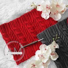 two red and black knitted headbands next to each other with flowers on them