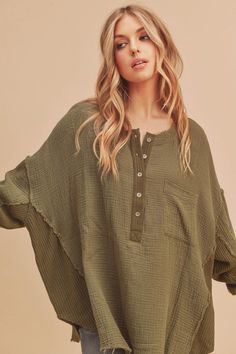 Stay comfy in the Majorie Top featuring a flowy cotton fabrication and effortless design with a button-up Henley style with thermal contrasting. -Color: Olive -Oversized fit -Curved hem -Long sleeves -Content: Self: 100% Cotton /Contrast: 65% Polyester 35% Cotton -Imported -Model is wearing a size Small Oversized Buttoned Tops For Loungewear, Oversized Button-down Tops For Layering, Oversized Buttoned Tops For Layering, Long Sleeve Blouse With Frayed Hem For Fall, Fall Long Sleeve Blouse With Frayed Hem, Casual Long Sleeve Blouse With Frayed Hem, Cozy Cotton Tops With Buttons, Cotton Long Sleeve Henley For Loungewear, Green Cotton Blouse For Loungewear