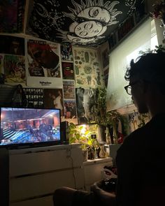 a man sitting in front of a tv on top of a dresser next to a window