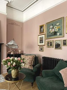 a living room with pink walls and green couches