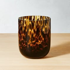 a brown and black vase sitting on top of a wooden table next to a white wall