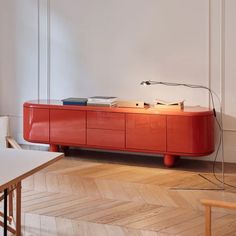 an orange sideboard with books on it in a living room next to a white wall