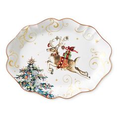 a white and gold christmas plate with a reindeer on it's back holding a red ribbon