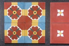 four tiles with flowers painted on them in different colors and shapes, one is red, the other is blue