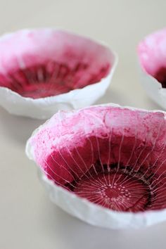 three paper bowls with red and white designs on the top one has a hole in it